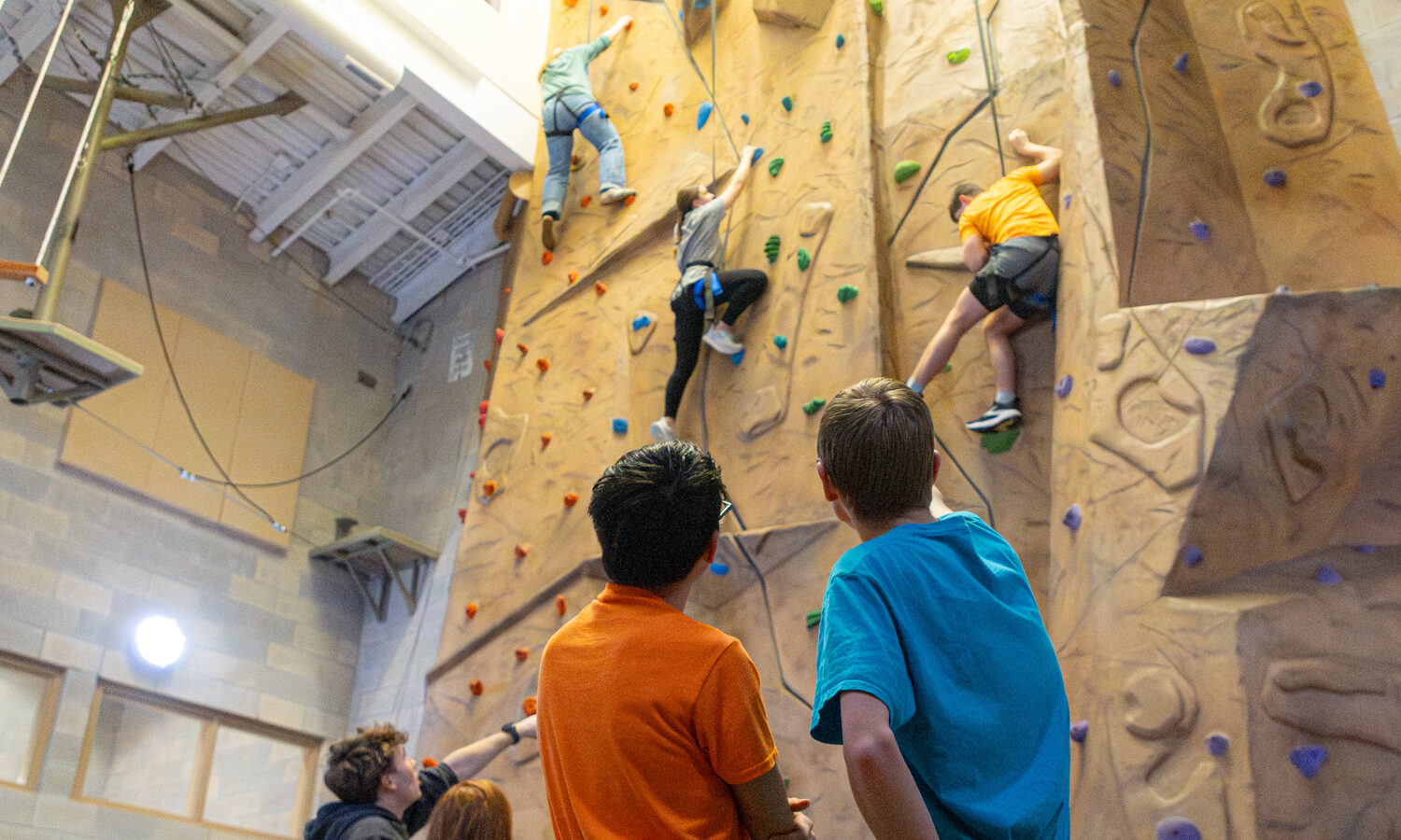 Teens climbing indoor rock wall